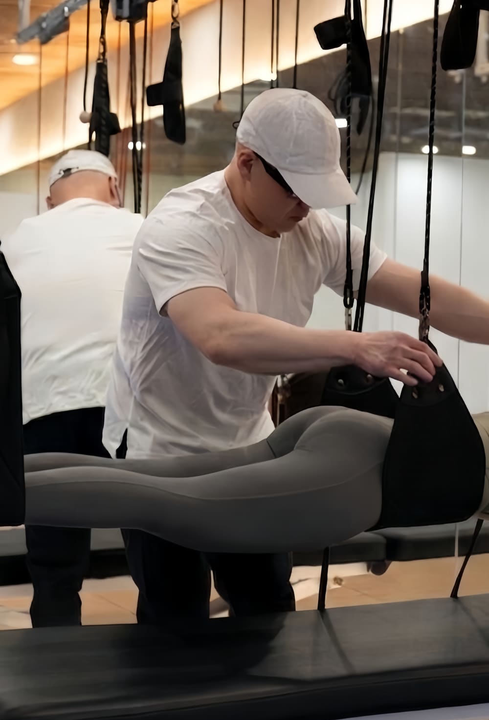 김형준 마스터 코치가 슬링 설비에서 회원의 자세를 잡아 주는 모습